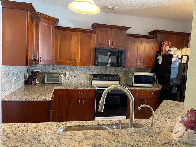 kitchen with light stone counters, decorative backsplash, a textured ceiling, and black appliances