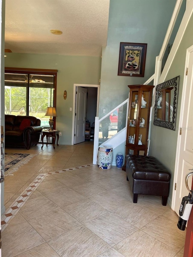 hallway featuring baseboards, a textured ceiling, and stairs