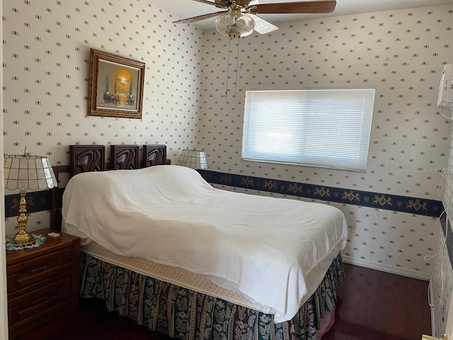 bedroom with ceiling fan, baseboards, dark wood finished floors, and wallpapered walls