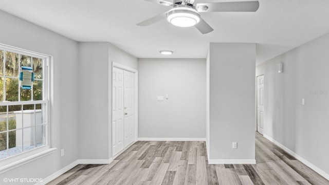 spare room with light wood-type flooring, a wealth of natural light, and ceiling fan