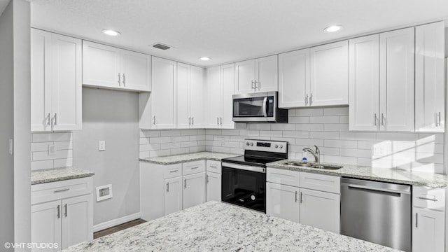 kitchen featuring light stone countertops, sink, white cabinets, and stainless steel appliances