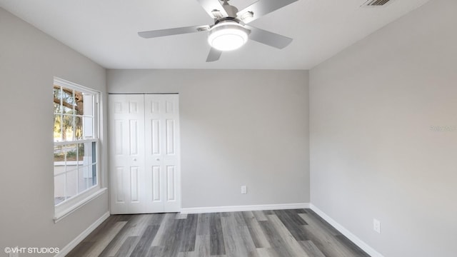 unfurnished bedroom with a closet, ceiling fan, and dark wood-type flooring