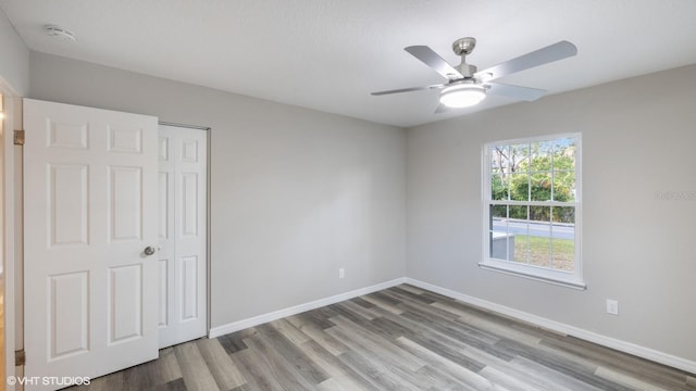 unfurnished bedroom featuring hardwood / wood-style floors, a closet, and ceiling fan