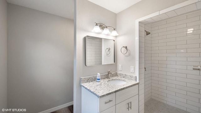 bathroom featuring a tile shower and vanity