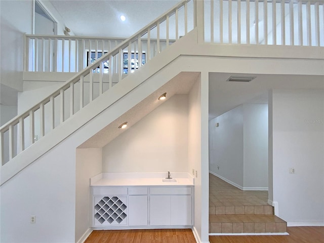 stairway featuring sink, high vaulted ceiling, and hardwood / wood-style flooring