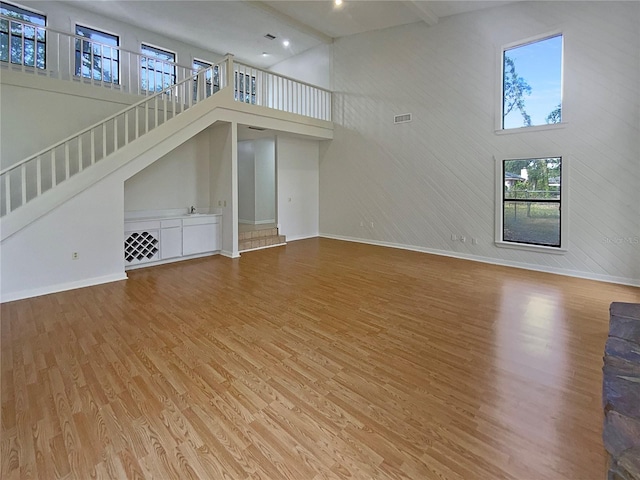 unfurnished living room featuring wood-type flooring and a towering ceiling