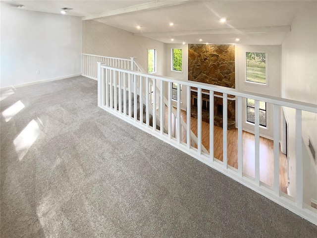 carpeted empty room with beam ceiling