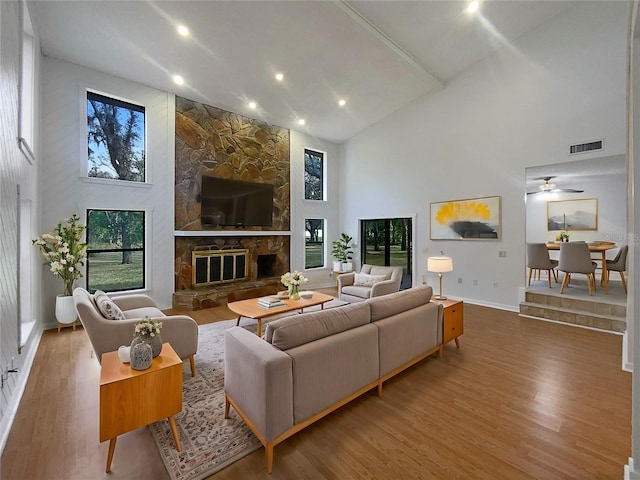 living room featuring hardwood / wood-style flooring, ceiling fan, a fireplace, and high vaulted ceiling