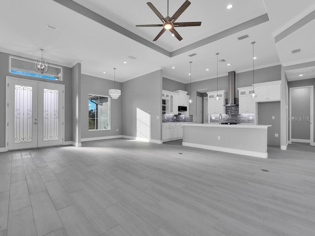 unfurnished living room with ornamental molding, ceiling fan with notable chandelier, and light wood-type flooring