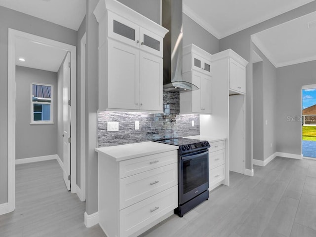 kitchen featuring wall chimney exhaust hood, black electric range, crown molding, decorative backsplash, and white cabinets