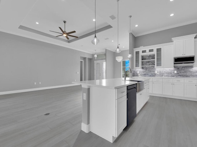 kitchen with black dishwasher, a raised ceiling, white cabinetry, and a kitchen island with sink