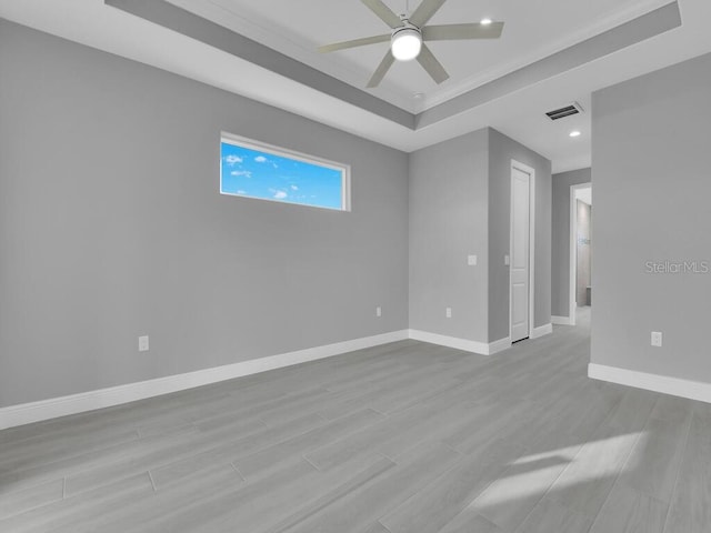 unfurnished room with a tray ceiling, ceiling fan, and light hardwood / wood-style flooring