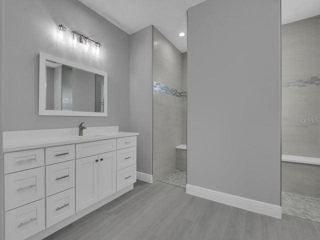 bathroom featuring vanity, wood-type flooring, and tiled shower