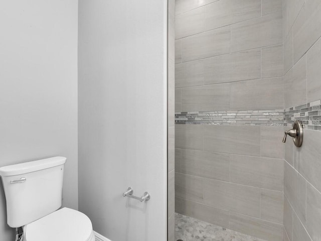 bathroom with tiled shower and toilet