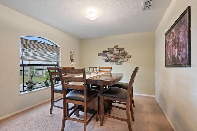 dining area featuring a textured ceiling and light colored carpet