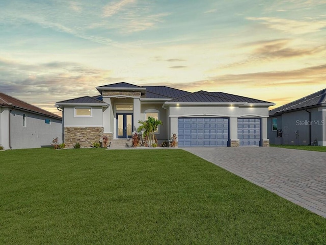 prairie-style house with a garage, a yard, and french doors