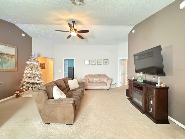 living room with a textured ceiling, light carpet, ceiling fan, and vaulted ceiling