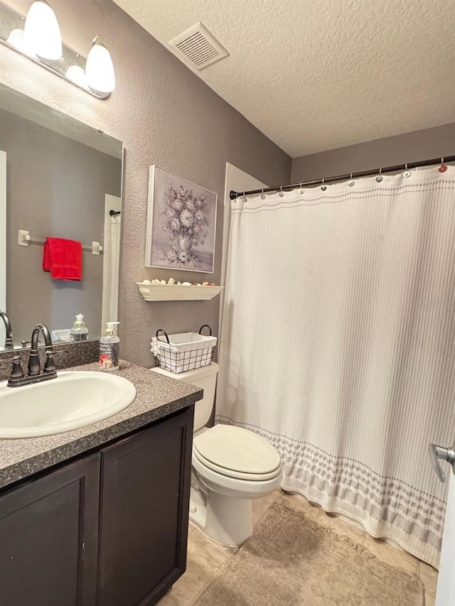 bathroom featuring vanity, a textured ceiling, toilet, and tile patterned flooring