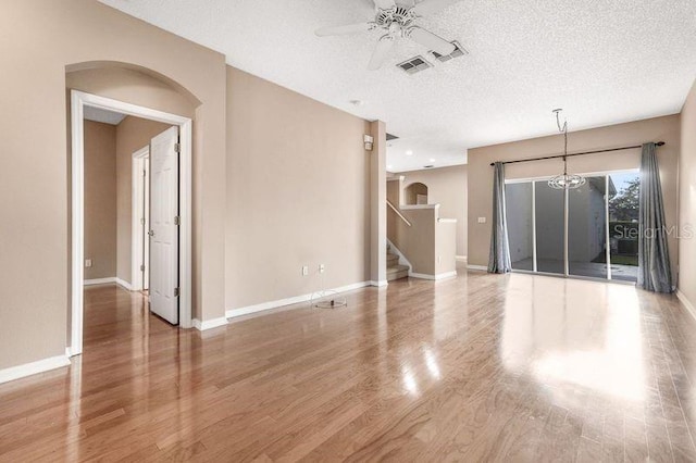 unfurnished room with ceiling fan with notable chandelier, hardwood / wood-style floors, and a textured ceiling