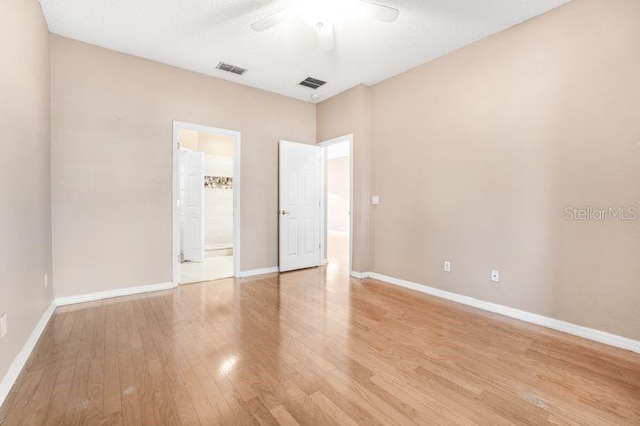 spare room with a textured ceiling, light wood-type flooring, and ceiling fan