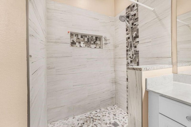 bathroom featuring a tile shower and vanity