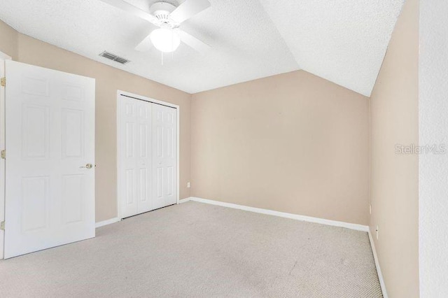 unfurnished bedroom featuring a closet, ceiling fan, lofted ceiling, and light colored carpet