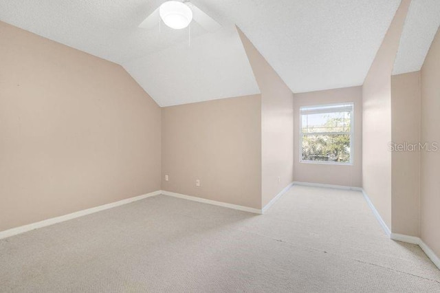 bonus room featuring light carpet, a textured ceiling, vaulted ceiling, and ceiling fan