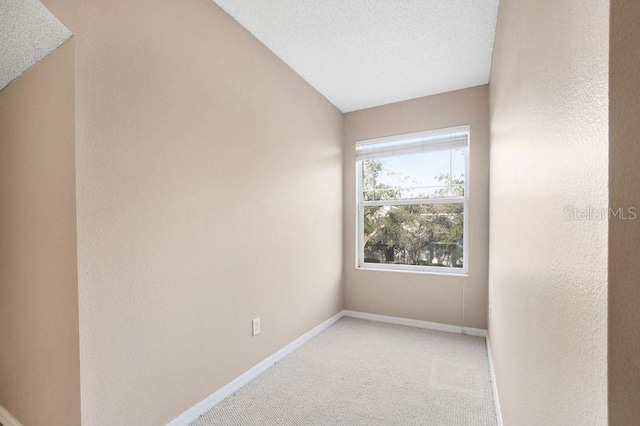 unfurnished room featuring carpet flooring, a textured ceiling, and lofted ceiling