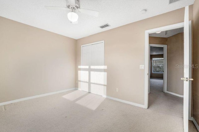 carpeted empty room featuring ceiling fan and a textured ceiling