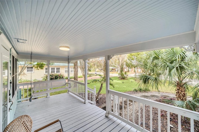 wooden terrace featuring a lawn and a porch