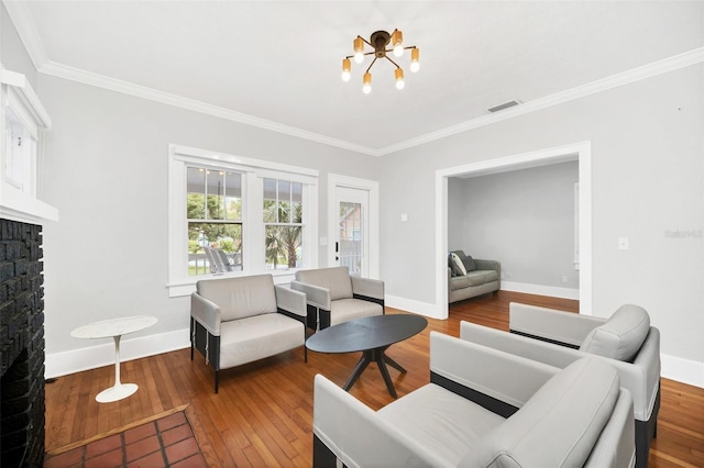 living room featuring hardwood / wood-style floors, ornamental molding, a fireplace, and a chandelier