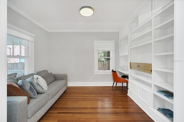 living room featuring a healthy amount of sunlight, built in desk, ornamental molding, and dark wood-type flooring