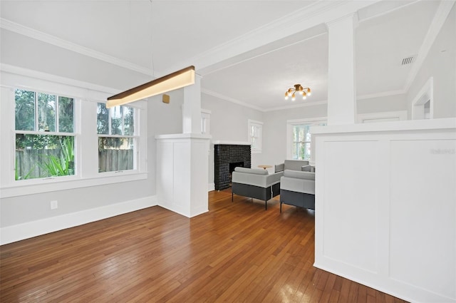 living room featuring dark hardwood / wood-style flooring, crown molding, plenty of natural light, and a brick fireplace