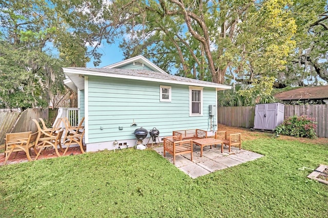 rear view of property with a lawn, a storage unit, and a patio area