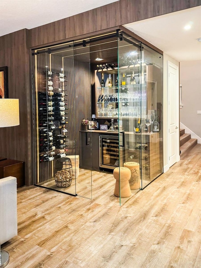 wine area featuring wood walls, wood-type flooring, and wine cooler