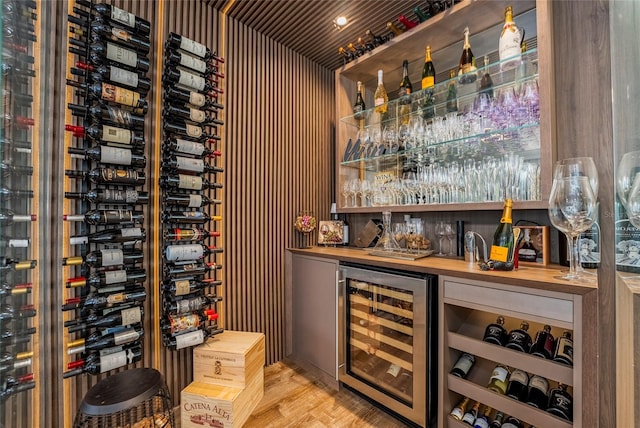 wine area featuring bar area, light hardwood / wood-style flooring, and beverage cooler