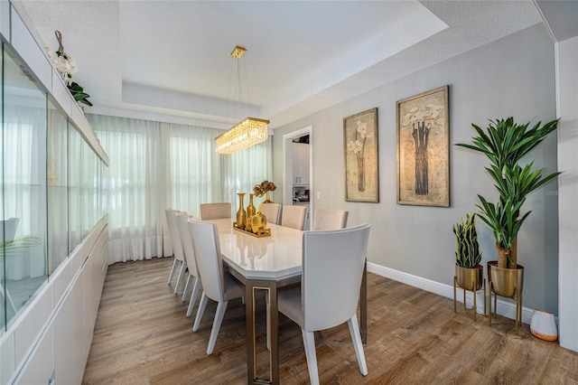 dining space featuring light hardwood / wood-style floors, a textured ceiling, and an inviting chandelier