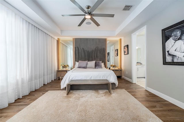 bedroom with hardwood / wood-style floors, ensuite bathroom, and ceiling fan