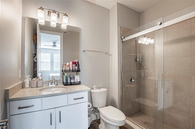 bathroom featuring ceiling fan, walk in shower, a textured ceiling, toilet, and vanity