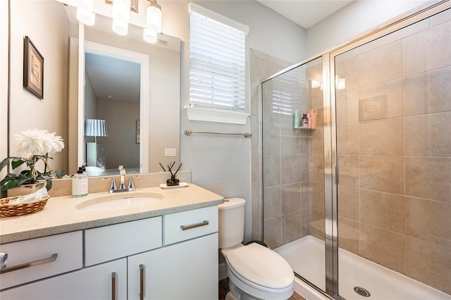 bathroom with vanity, a shower with shower door, and toilet