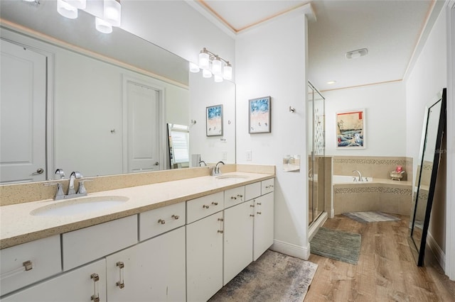 bathroom featuring wood-type flooring, vanity, shower with separate bathtub, and ornamental molding