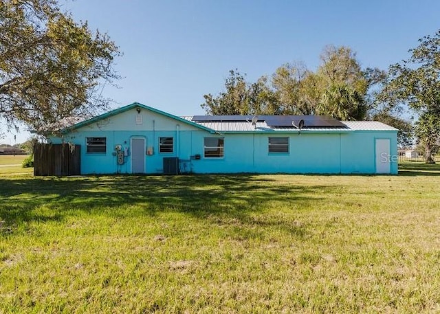 back of house with solar panels, cooling unit, and a yard