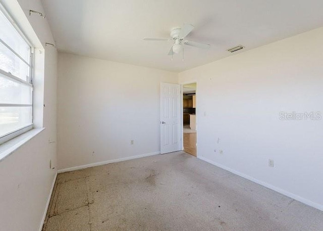 carpeted spare room with a wealth of natural light and ceiling fan