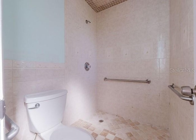 bathroom featuring tiled shower, tile walls, and toilet