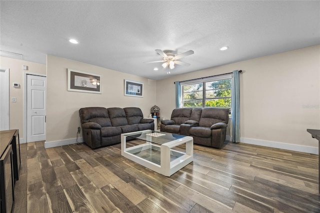 living room with ceiling fan, dark hardwood / wood-style flooring, and a textured ceiling