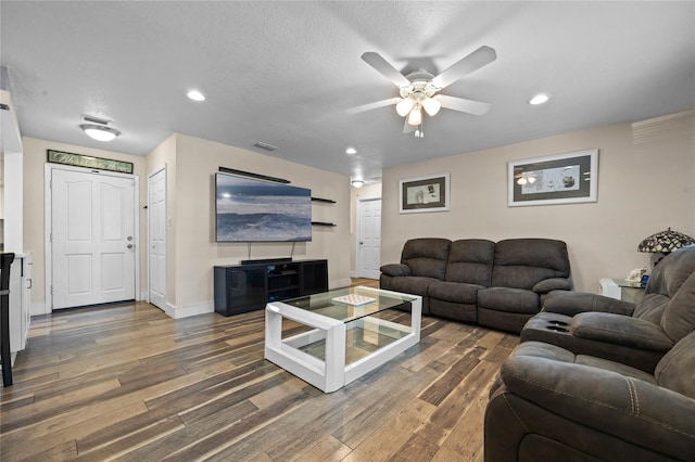 living room featuring ceiling fan, dark hardwood / wood-style flooring, and a textured ceiling