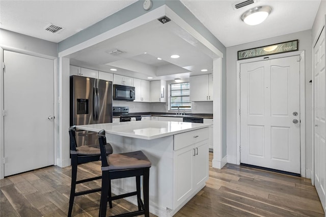 kitchen featuring a kitchen bar, appliances with stainless steel finishes, sink, a center island, and white cabinetry