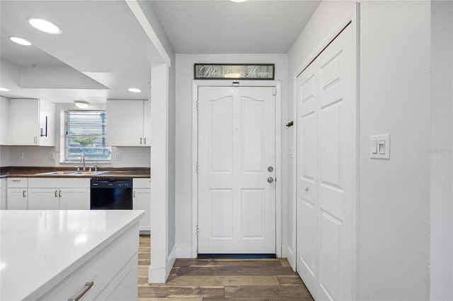 kitchen with sink, dark hardwood / wood-style flooring, white cabinetry, and black dishwasher