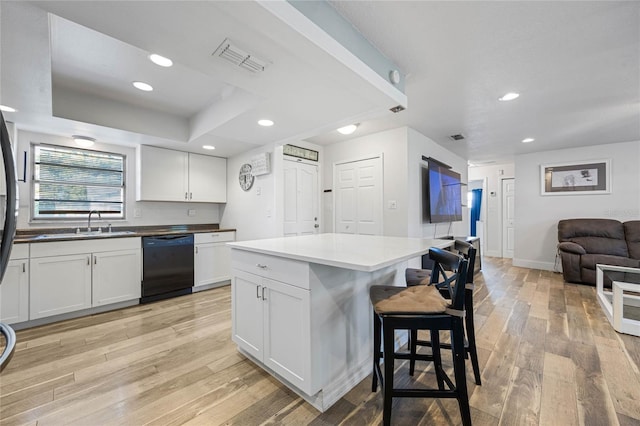 kitchen with sink, a center island, black dishwasher, light hardwood / wood-style flooring, and white cabinets