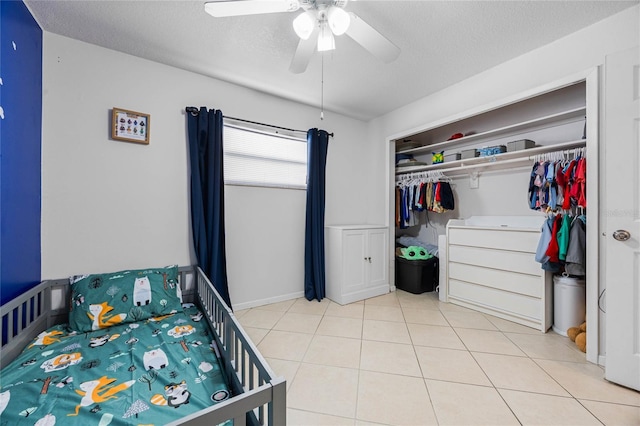 bedroom featuring light tile patterned floors, a textured ceiling, a closet, and ceiling fan